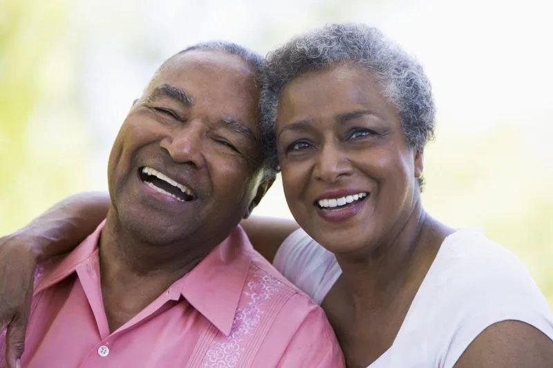 Senior couple laughing together, arms around each other.