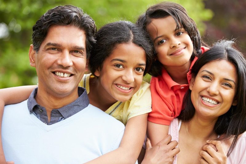 Smiling family of four outdoors in natural light.