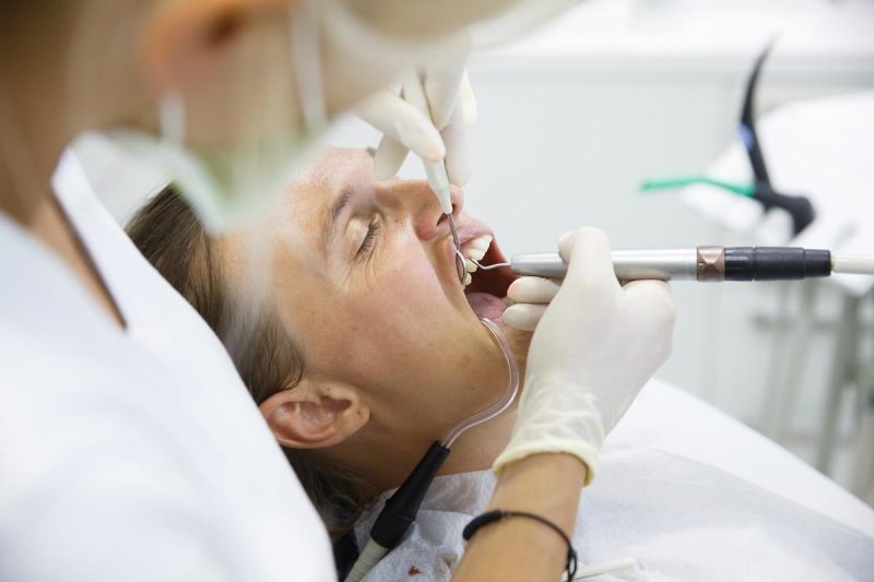 Patient receiving dental exam with tools in mouth.